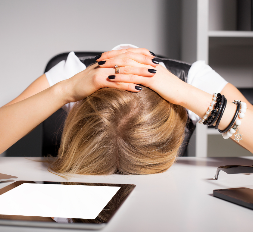 woman with head down on work desk appearing stressed out
