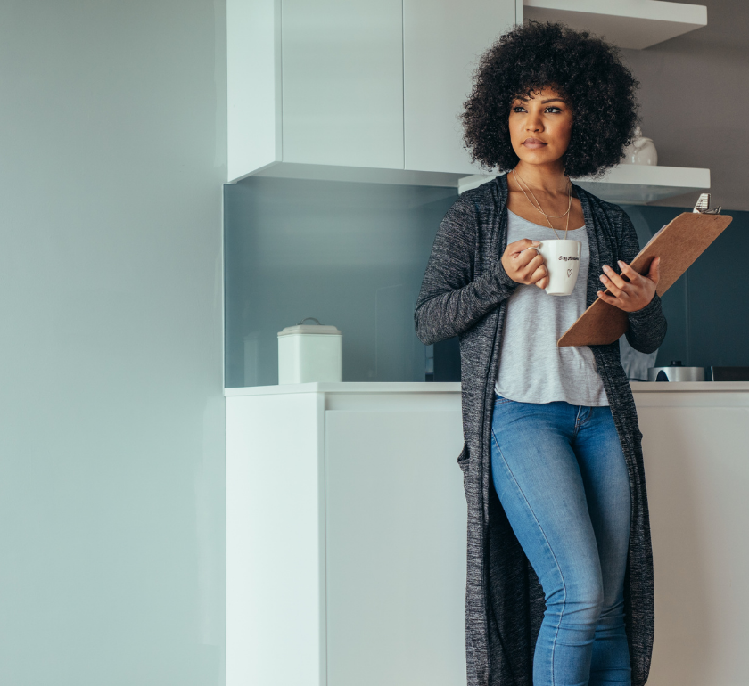 woman standing with cup of coffee and clipboard researching endometriosis symptoms