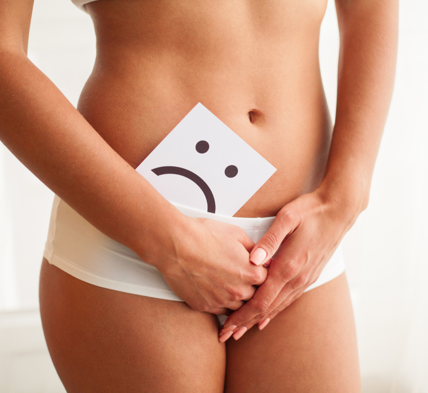woman with endometriosis pain covering pelvis with a card with a sad face tucked into underwear