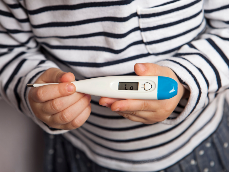 woman shows a low temperature displayed on basal body temperature thermometer