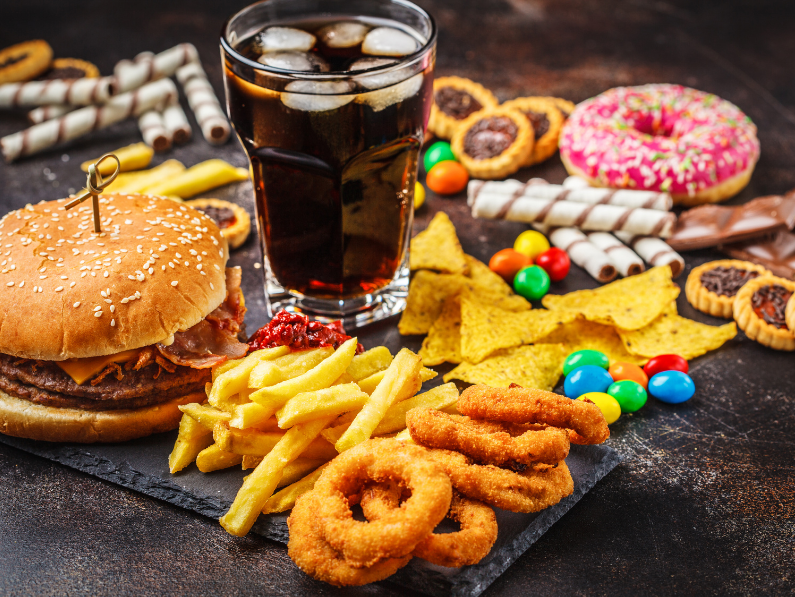 burger fries onion rings soda candy and junk food on a table different types of inflammatory foods
