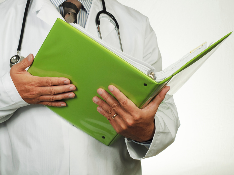 doctor holding a green notebook overlooking patients medical information