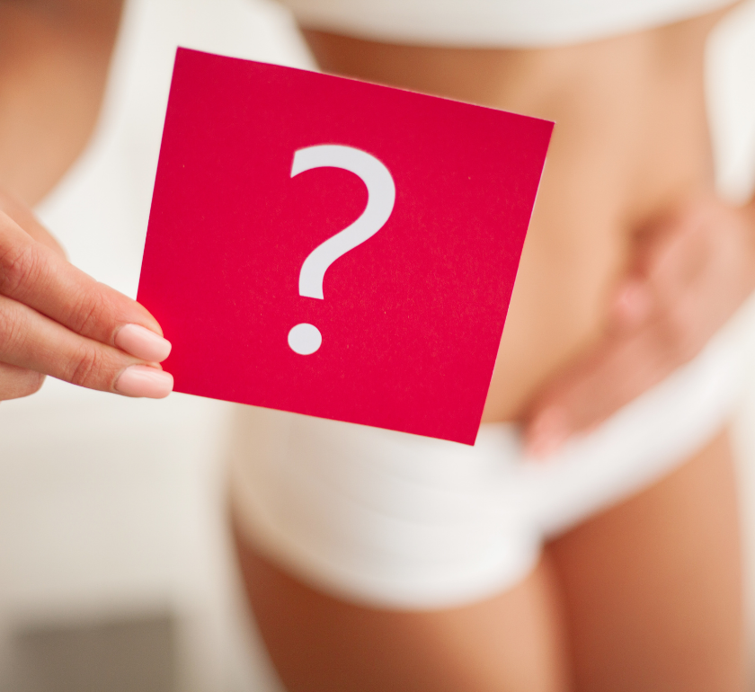 woman with hand on stomach holding a red card with a question mark signifying a missing period as a perimenopause symptom