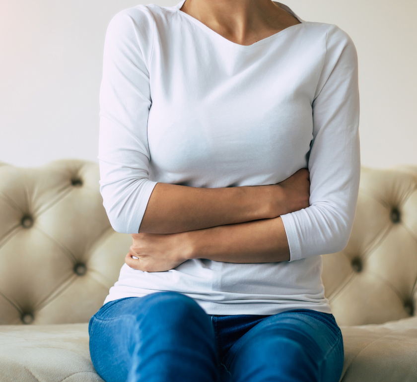 woman sitting on couch with arms wrapped around herself thinking about the various endometriosis facts