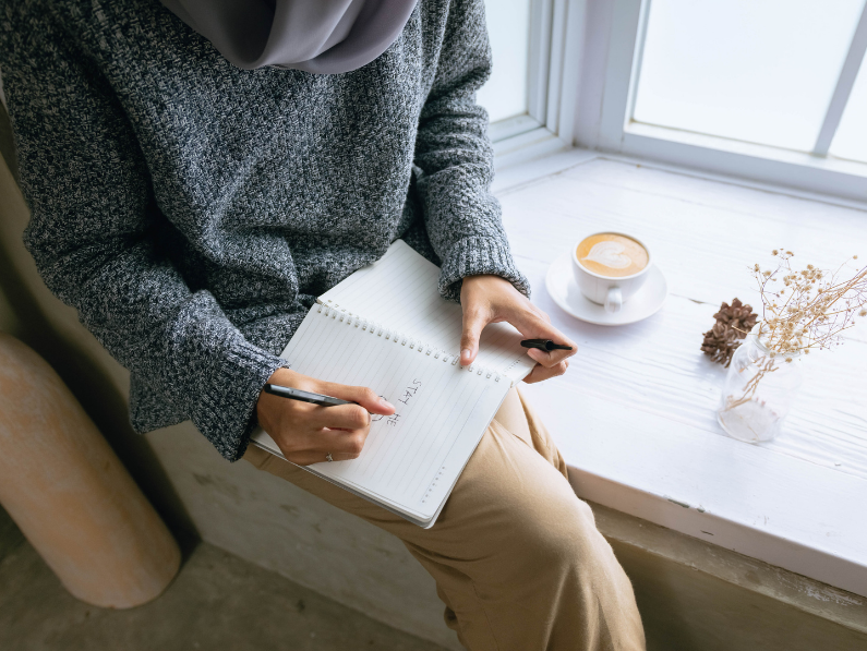 woman sitting in nook with coffee journaling about healthy living with endometriosis