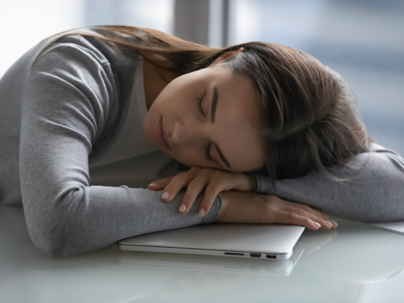 woman resting head on arms on laptop taking a nap