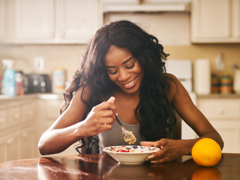 woman smiling and eating oatmeal at dining room table